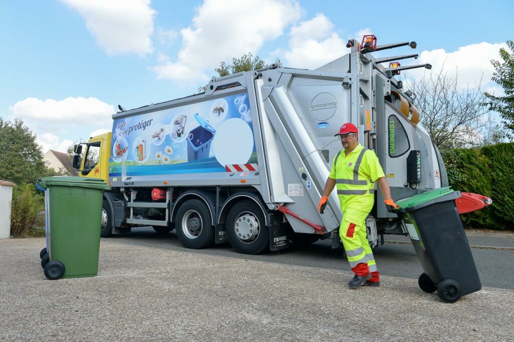 Un éboueur ramasse les poubelles grises pendant la collecte