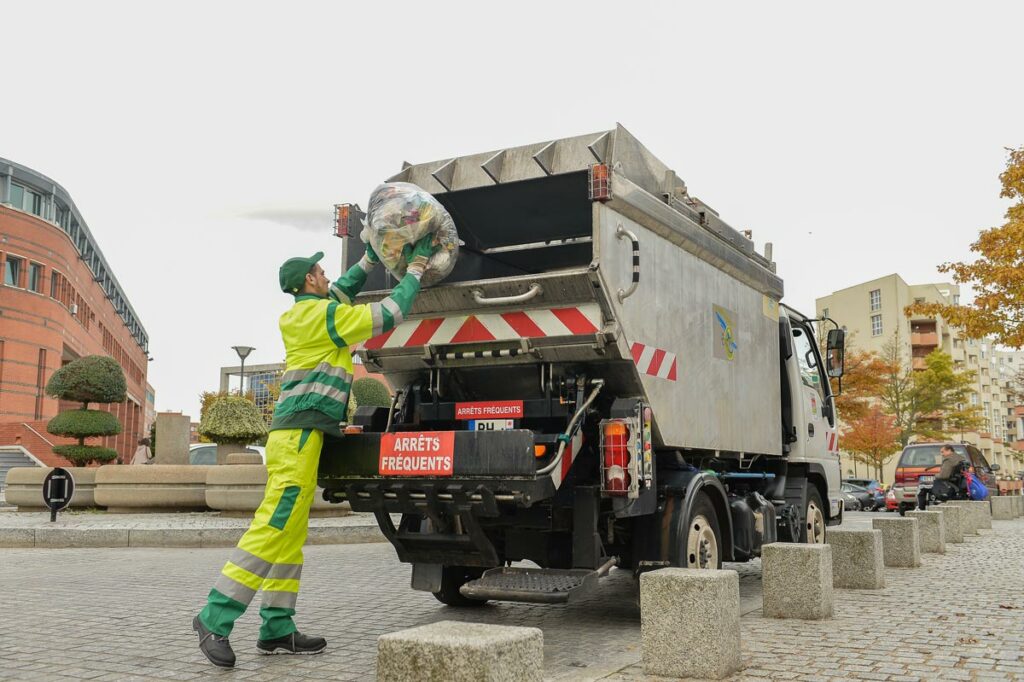Un éboueur jette une poubelle dans un camion poubelle